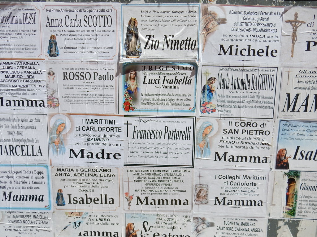 Death remembrances are posted on boards in Carloforte.